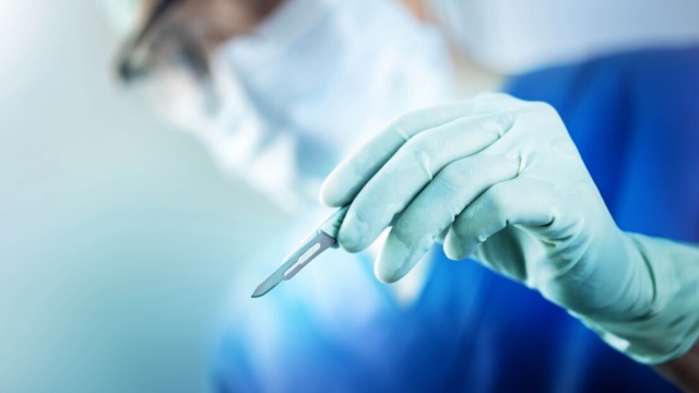 background image of surgeon holding scalpel during surgery