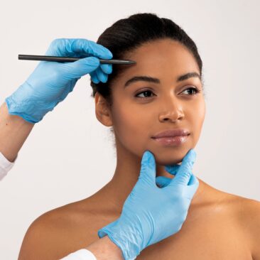 gloved hands drawing on patient's forehead