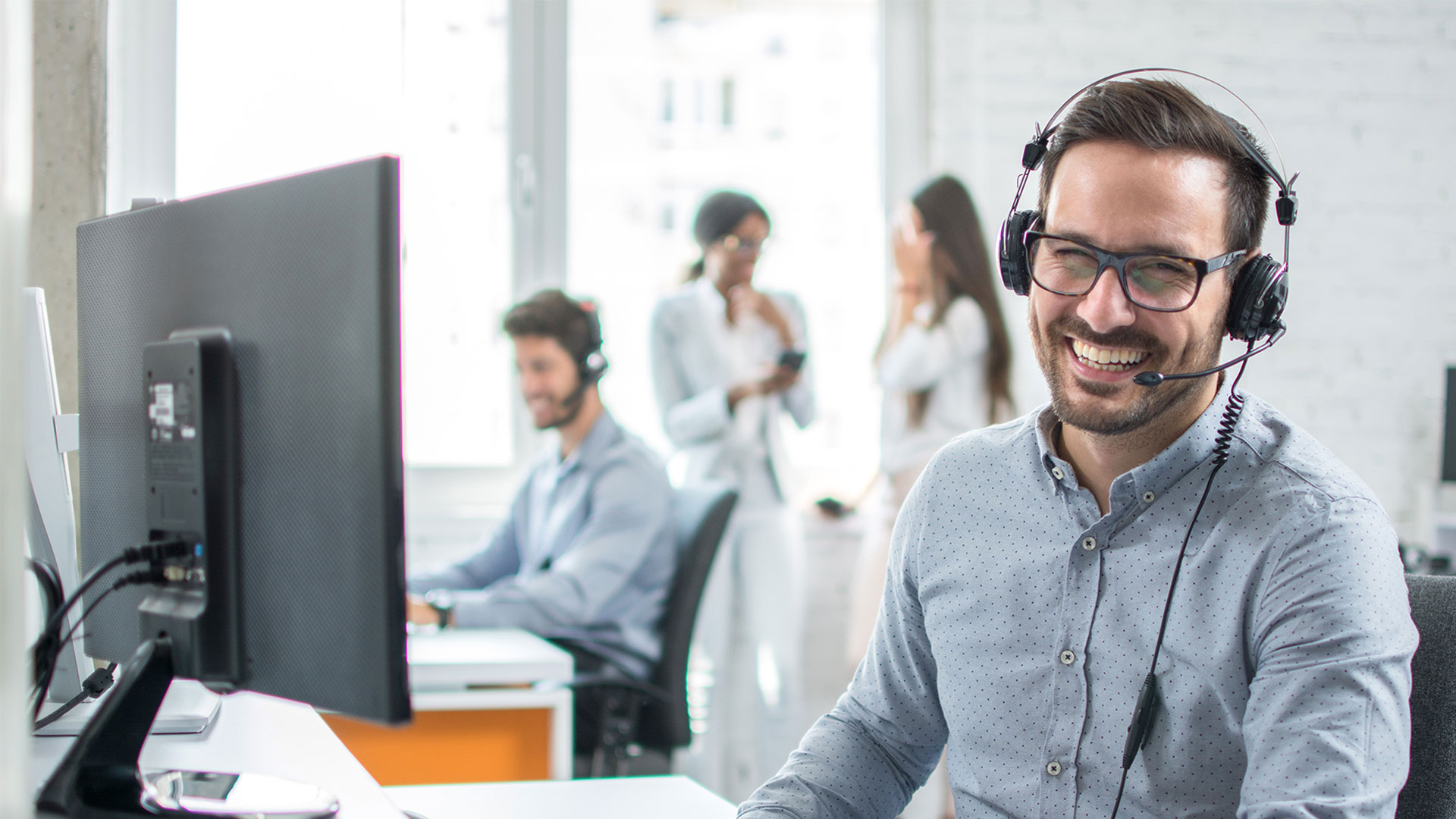 Customer service center with man at workstation wearing a headset