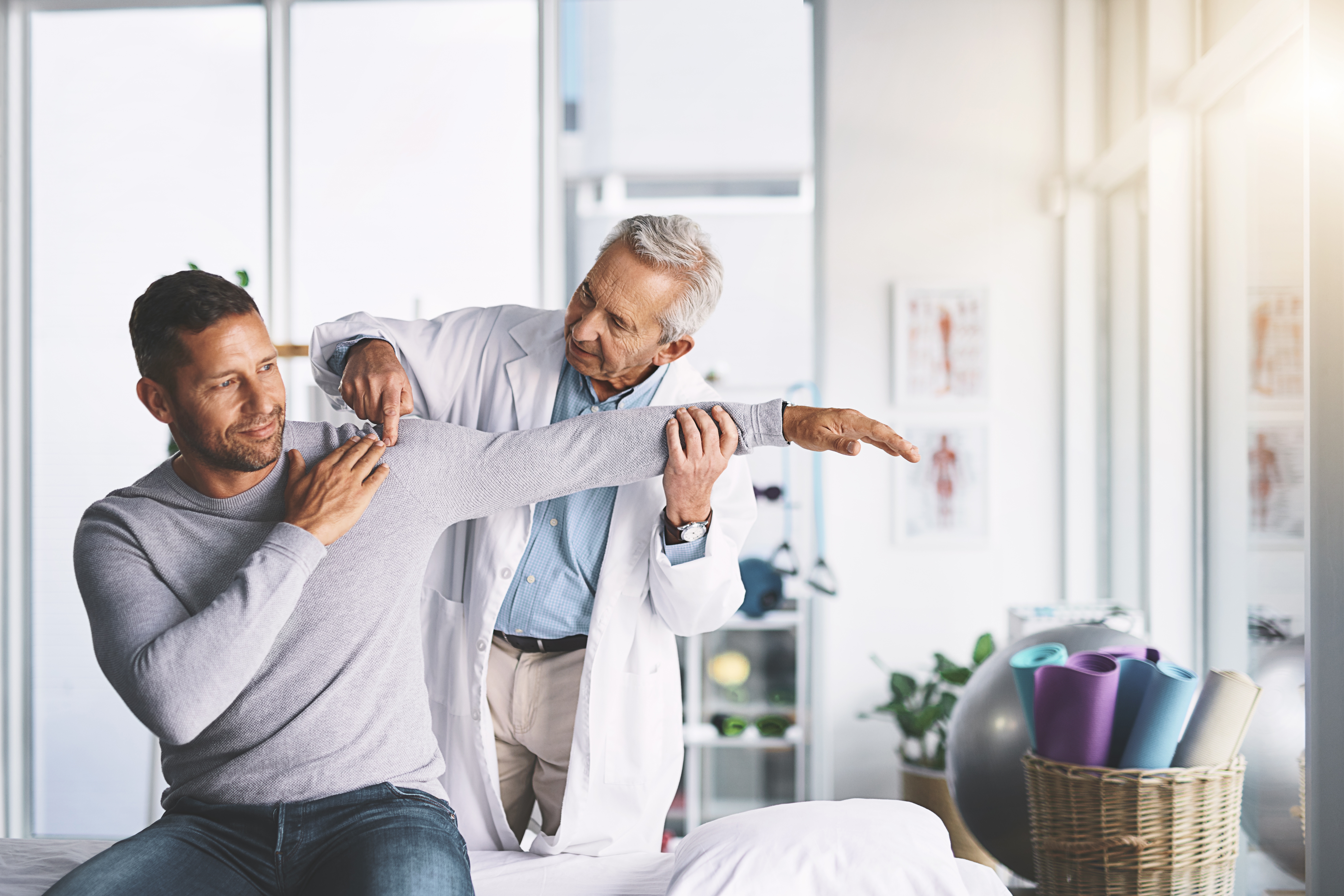 Orthopedic doctor looks at mans shoulder