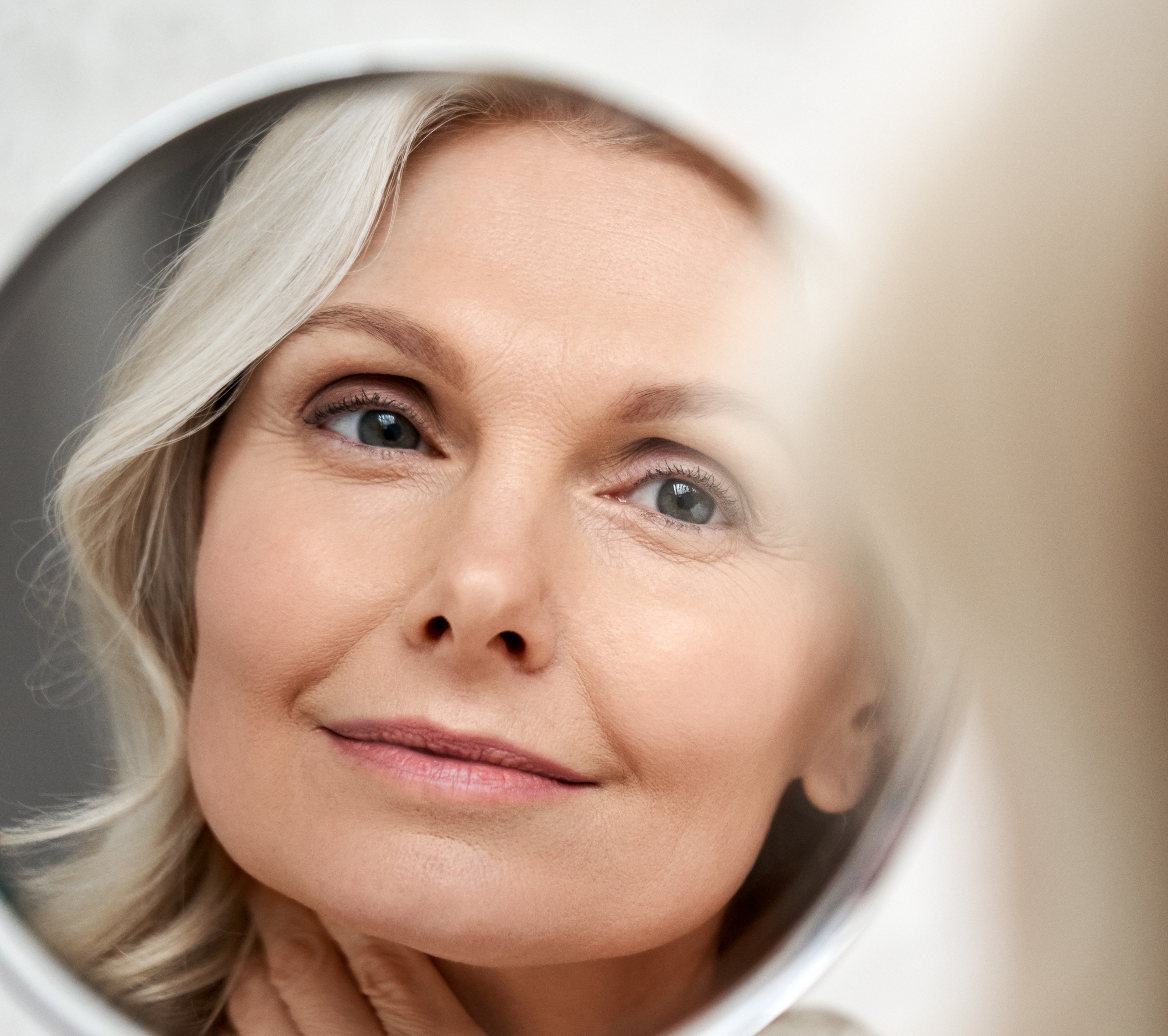 Beautiful woman with clear skin looking in the mirror.